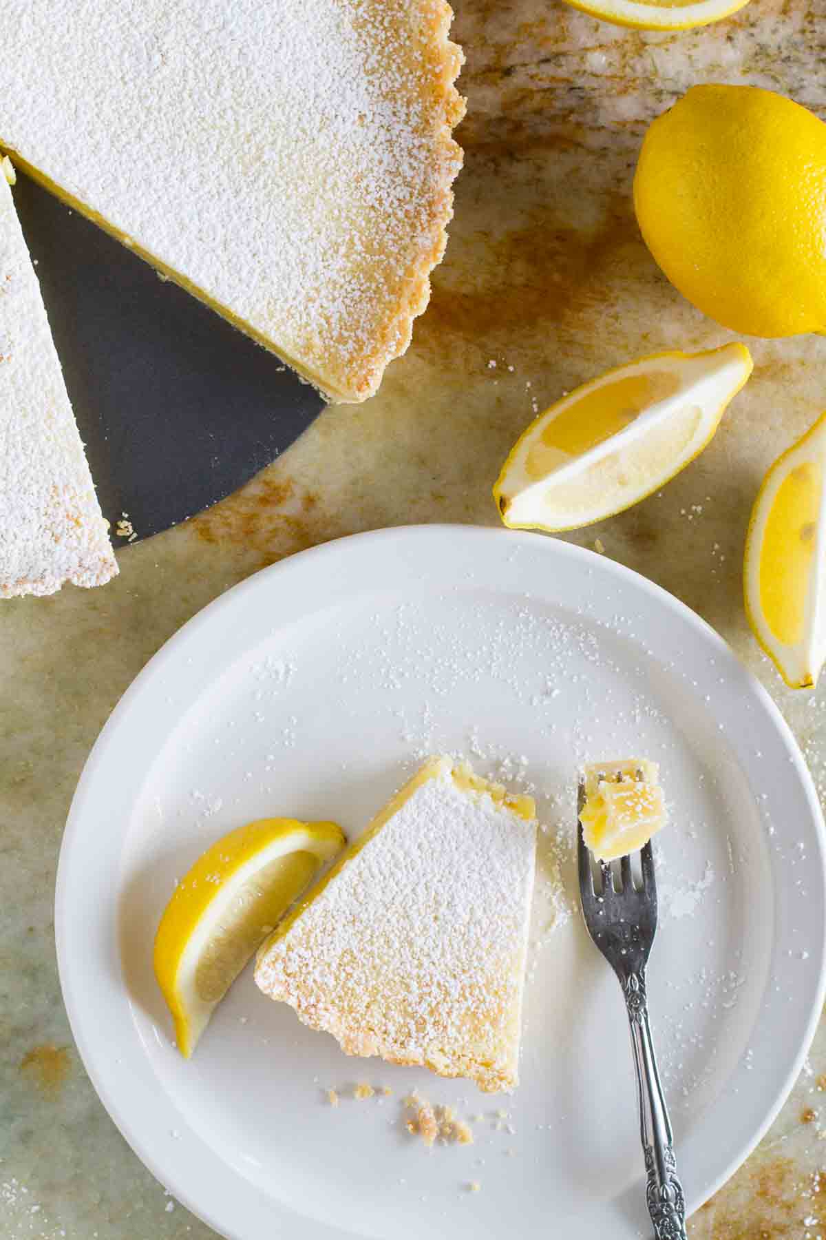Overhead view of slice of shortbread lemon tart with a bite taken from it on a fork.
