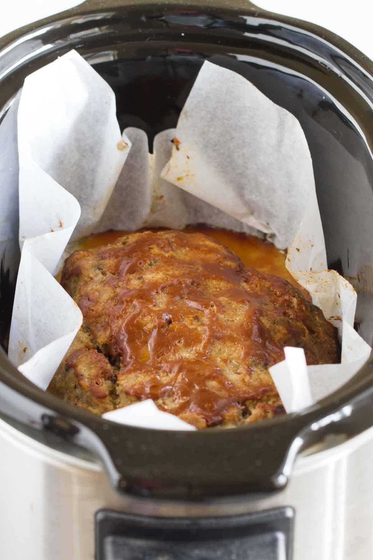 Healthy Slow Cooker Turkey Meatloaf inside of a slow cooker with parchment paper lining the crockpot