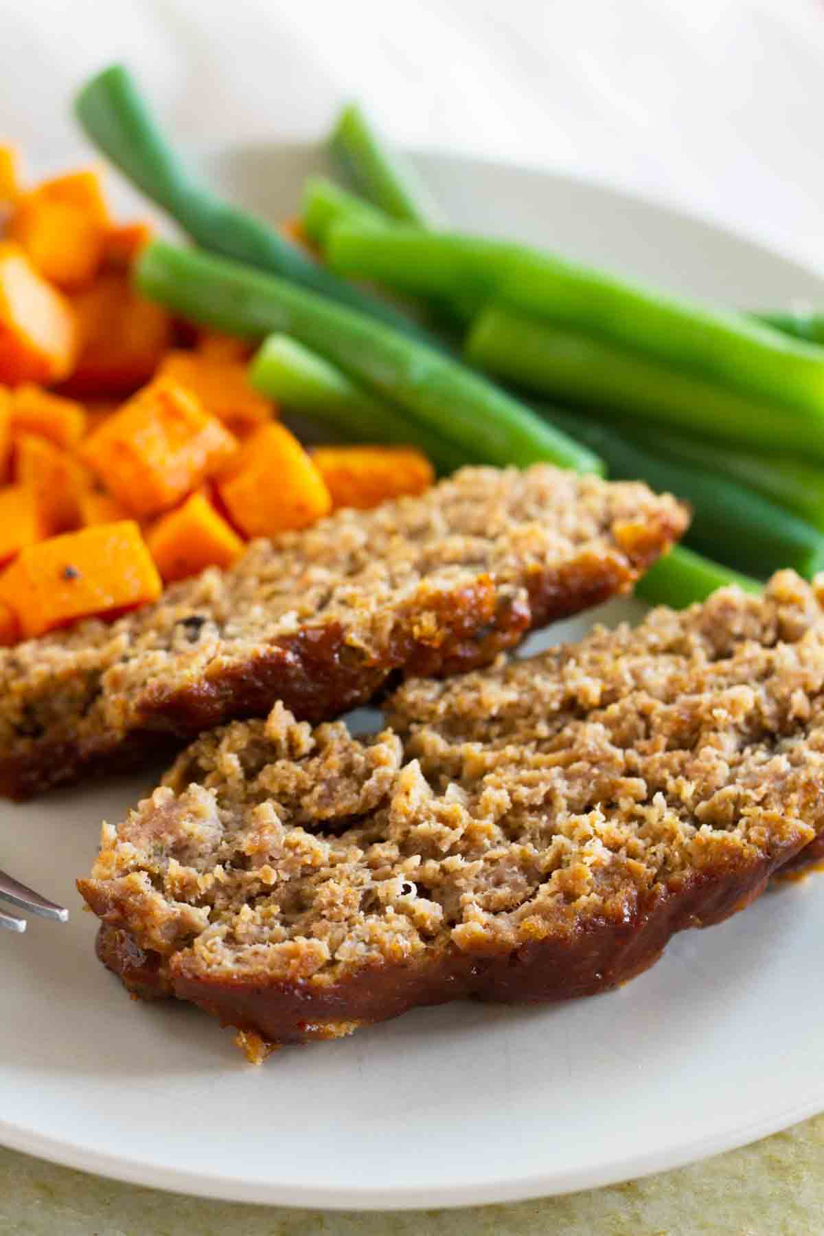 slices of slow cooker turkey meatloaf on a plate with vegetables