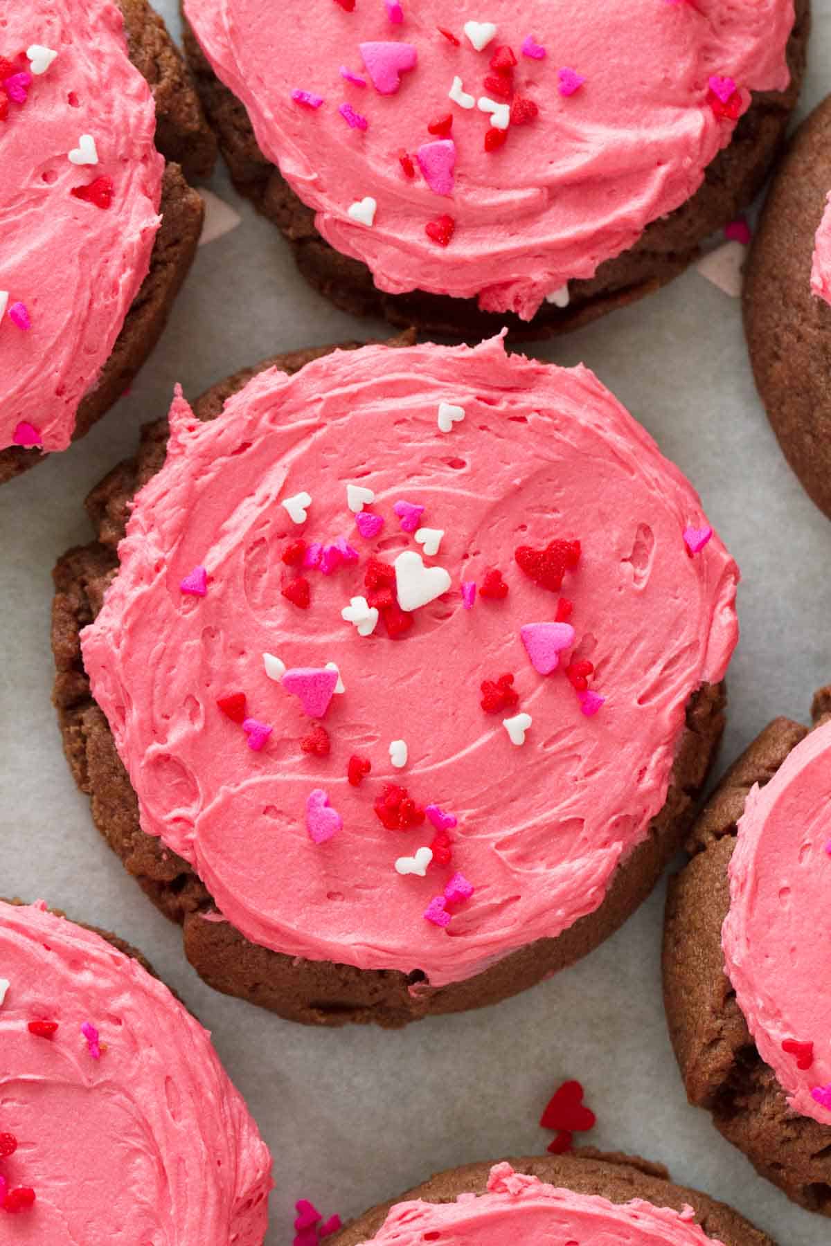 overhead view of chocolate sugar cookie with pink frosting and sprinkles