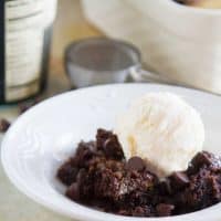 Gooey Caramel Chocolate Dump Cake in a bowl with a scoop of vanilla ice cream.