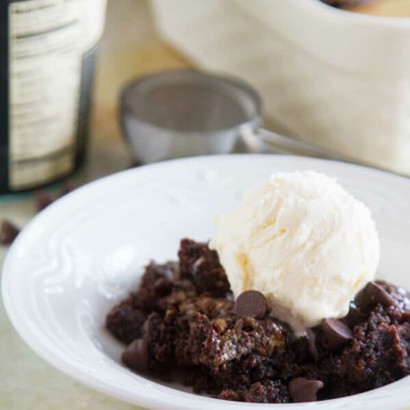 Gooey Caramel Chocolate Dump Cake in a bowl with a scoop of vanilla ice cream.