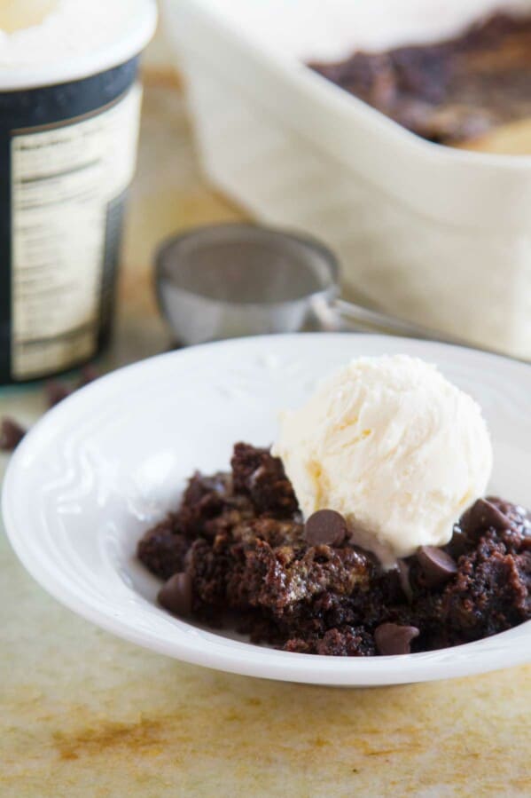 Gooey Caramel Chocolate Dump Cake in a bowl with a scoop of vanilla ice cream.