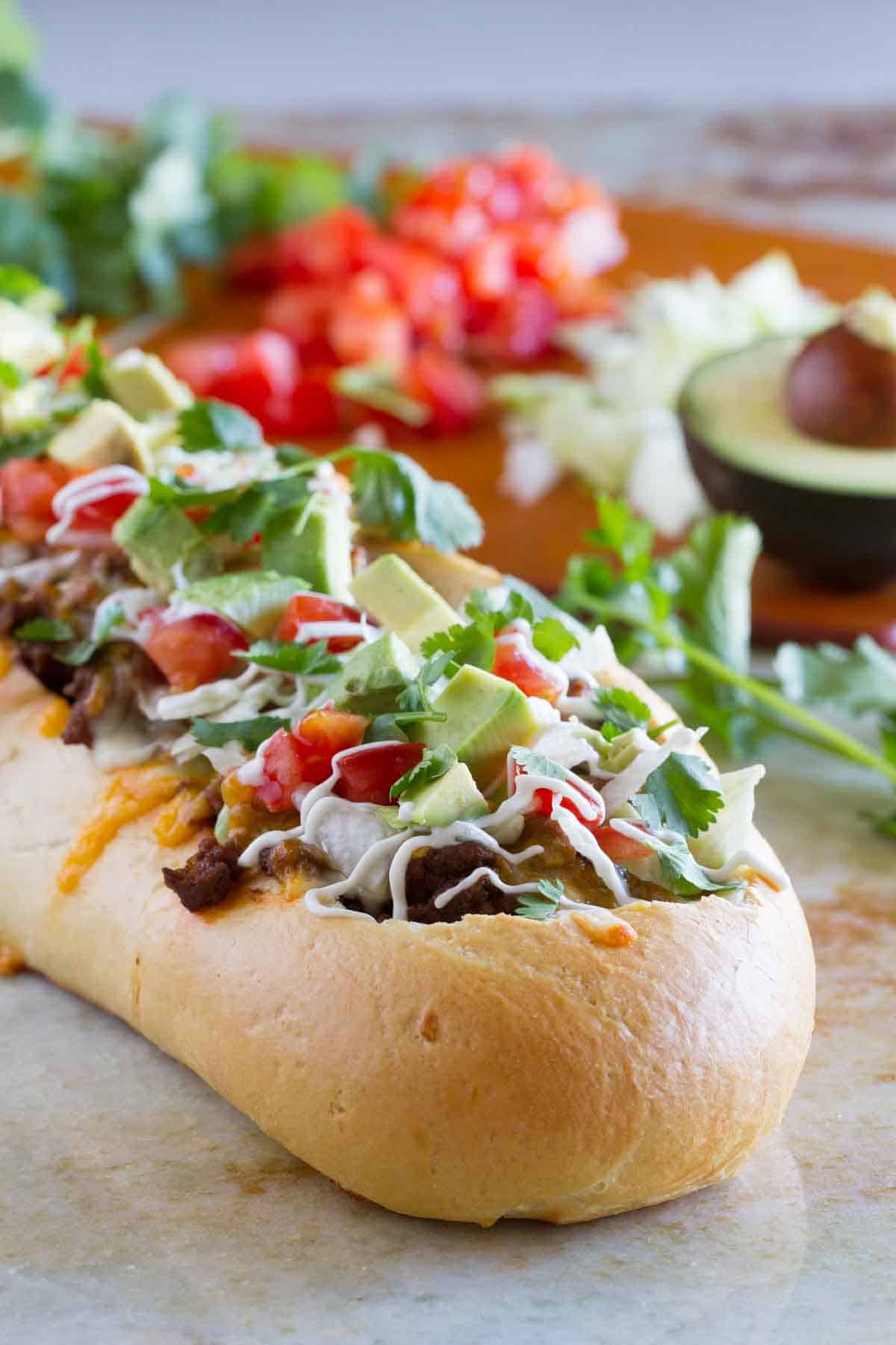 Loaf of french bread filled with lots of taco toppings.