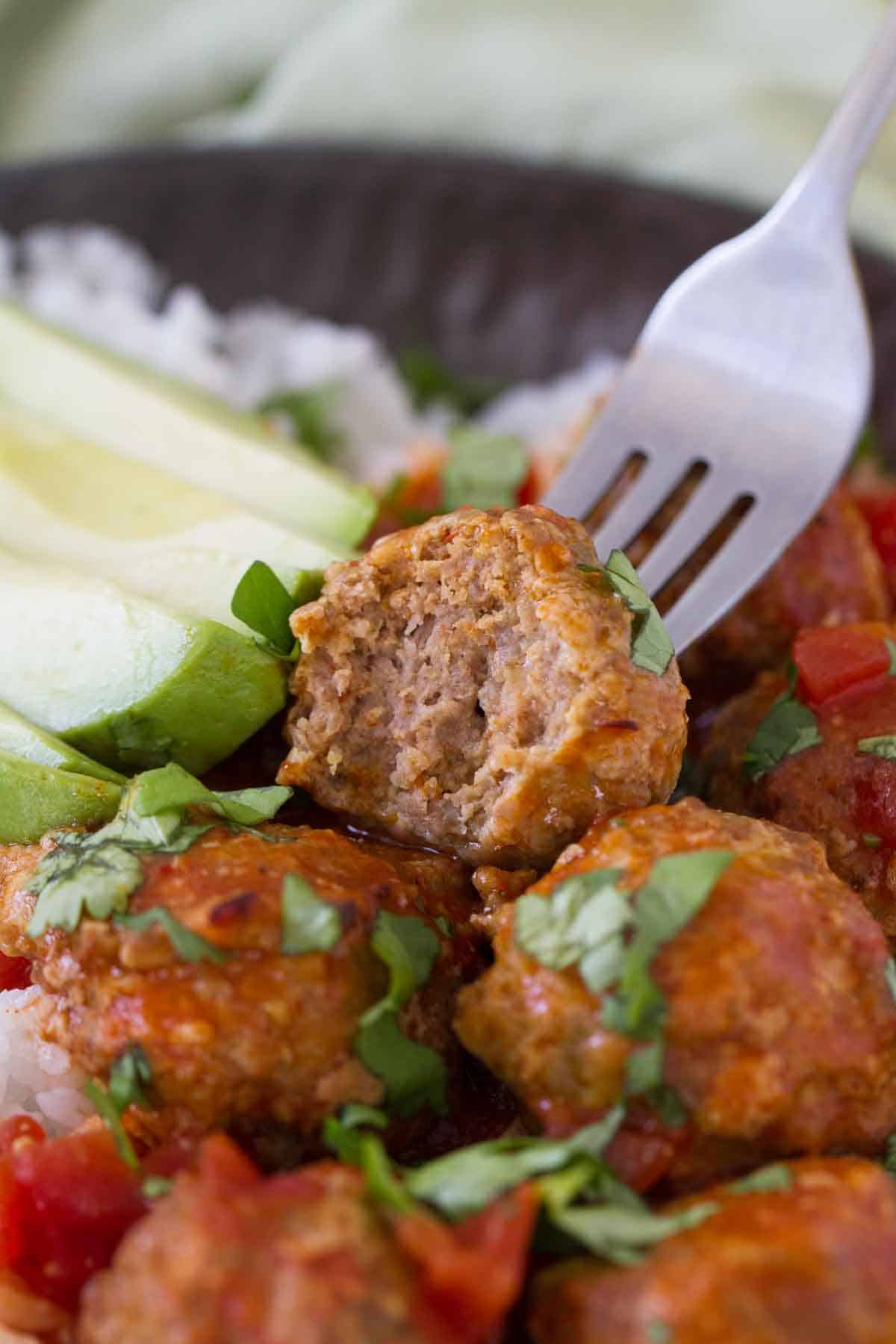 Slow Cooker Mexican Meatball with a bite taken from it to show texture.
