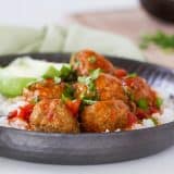 Taco spiced meatballs are slow cooked in an easy enchilada sauce. Serve the over rice or tortilla chips or turn them into a Tex-Mex style hoagie sandwich!