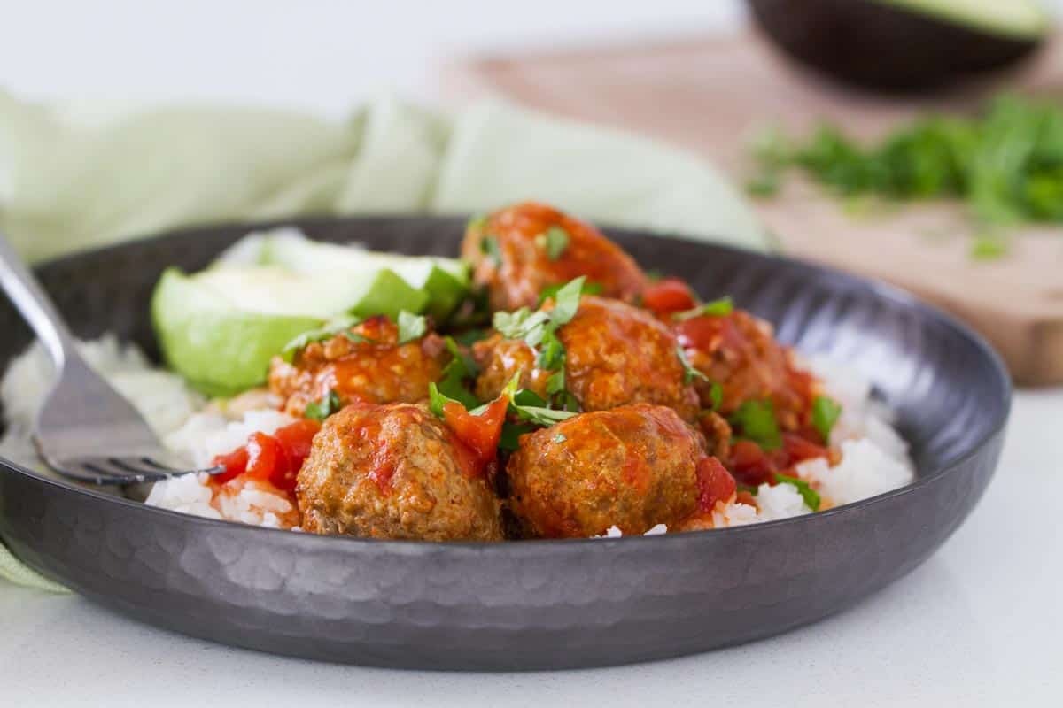 Slow Cooker Mexican Meatballs over rice in a deep plate.