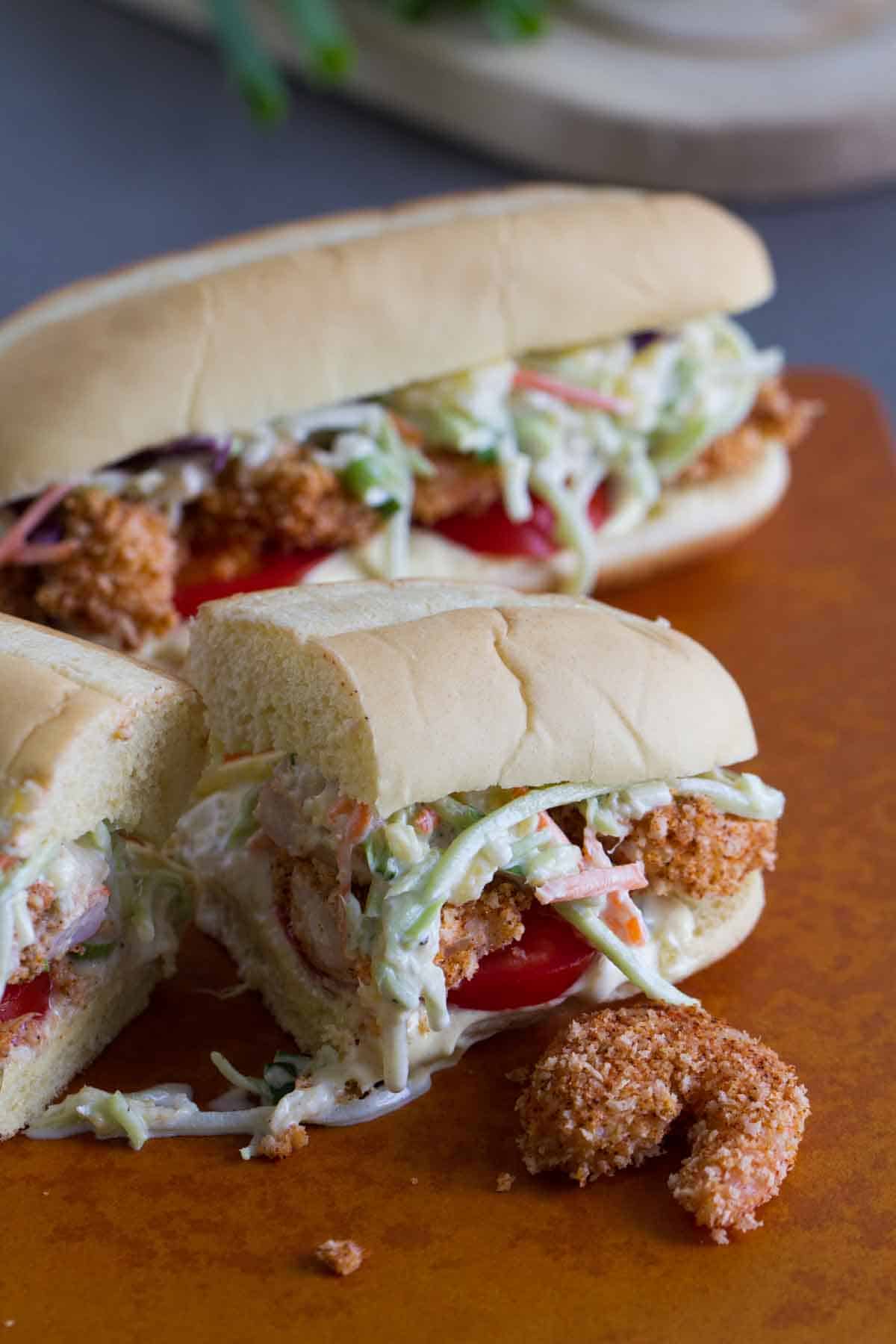 Shrimp Po Boy Sandwich with Pineapple Slaw cut in half with a shrimp on the side.