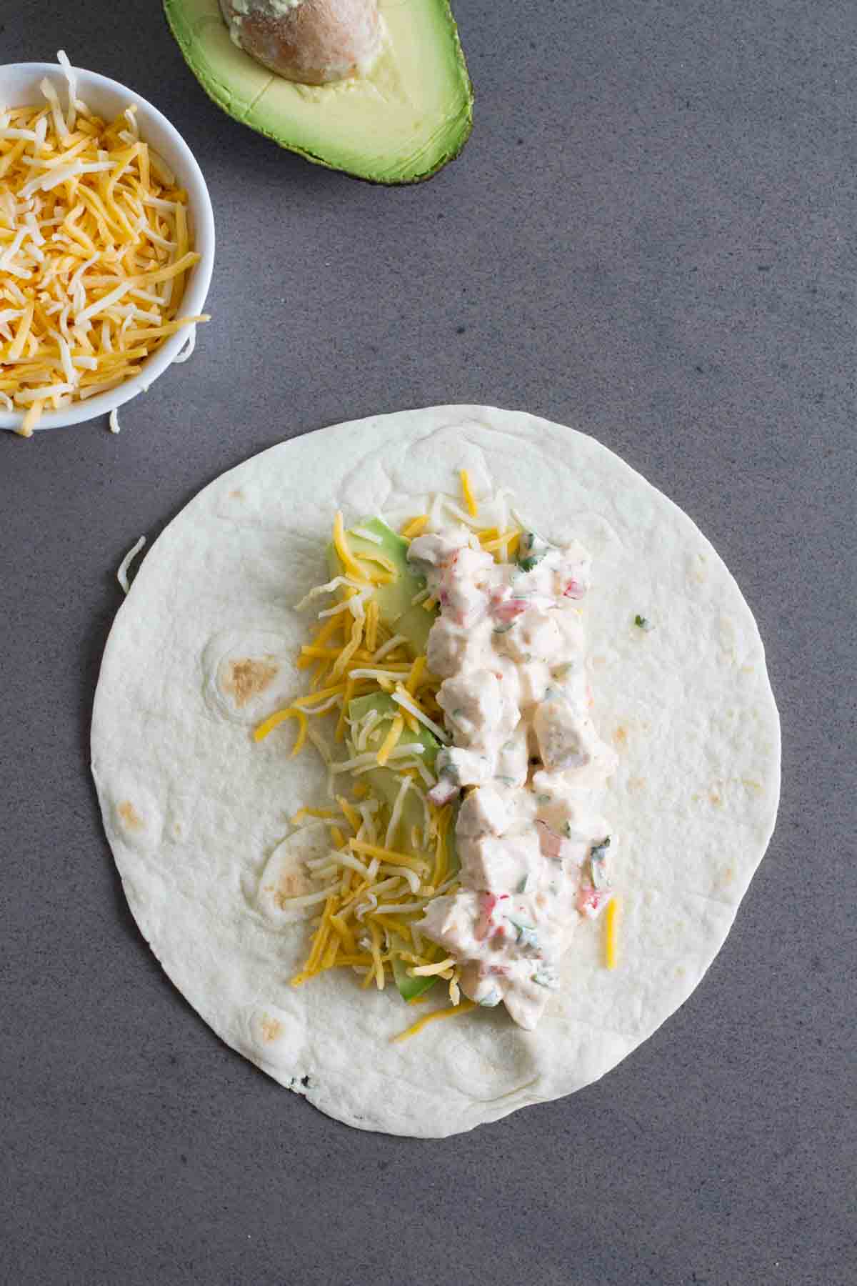 Adding tex-mex chicken salad to a tortilla to make a wrap.