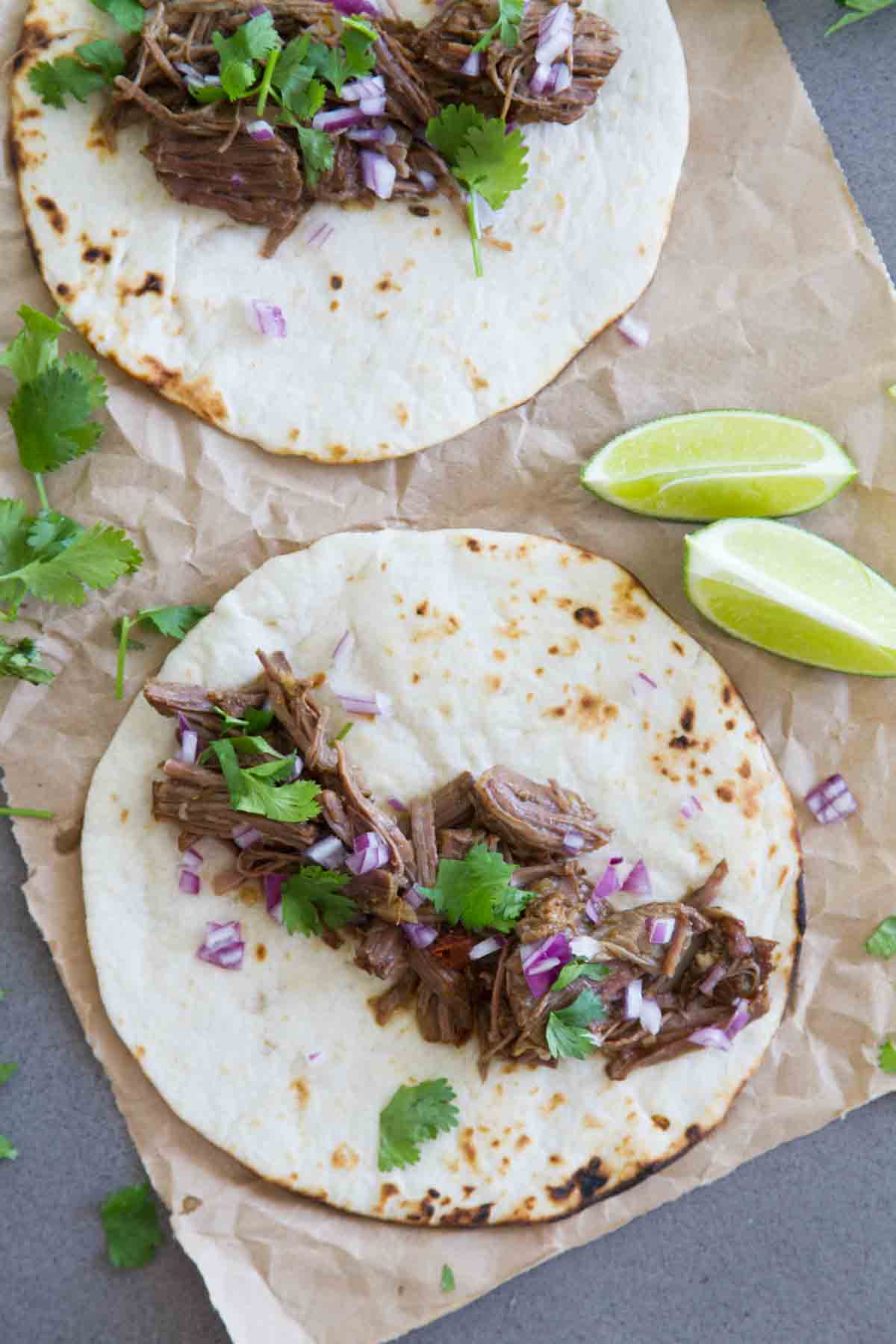 overhead view of 2 tacos with beef barbacoa and cilantro