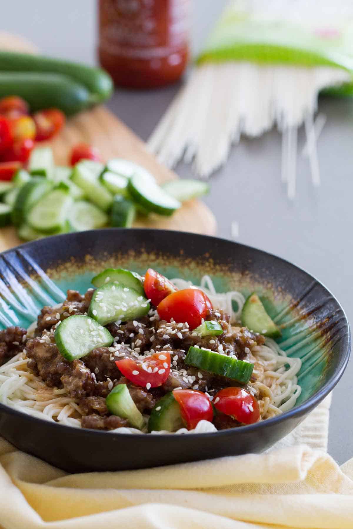 Spicy Pork Noodle Bowl with spicy pork served over Chinese noodles and topped with fresh vegetables.