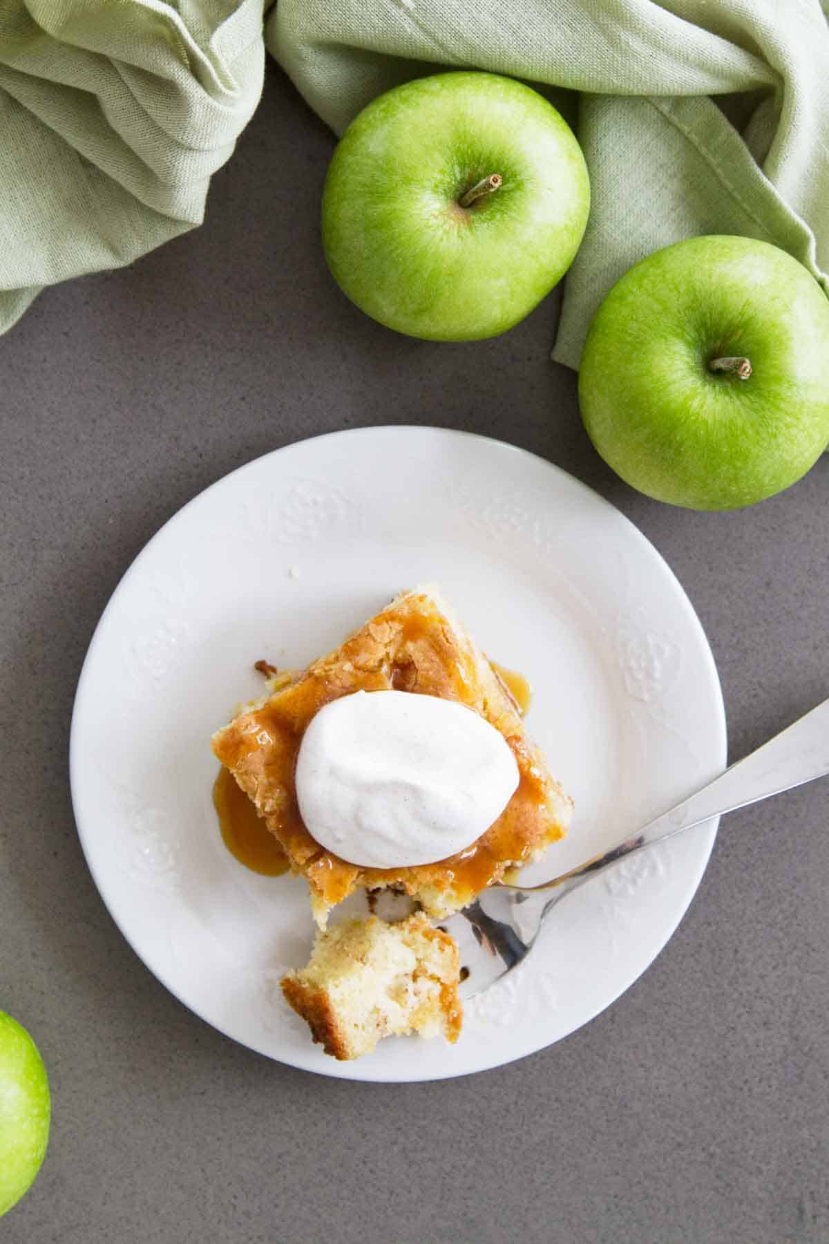 overhead view of a slice of apple cinnamon cake with apples on the table