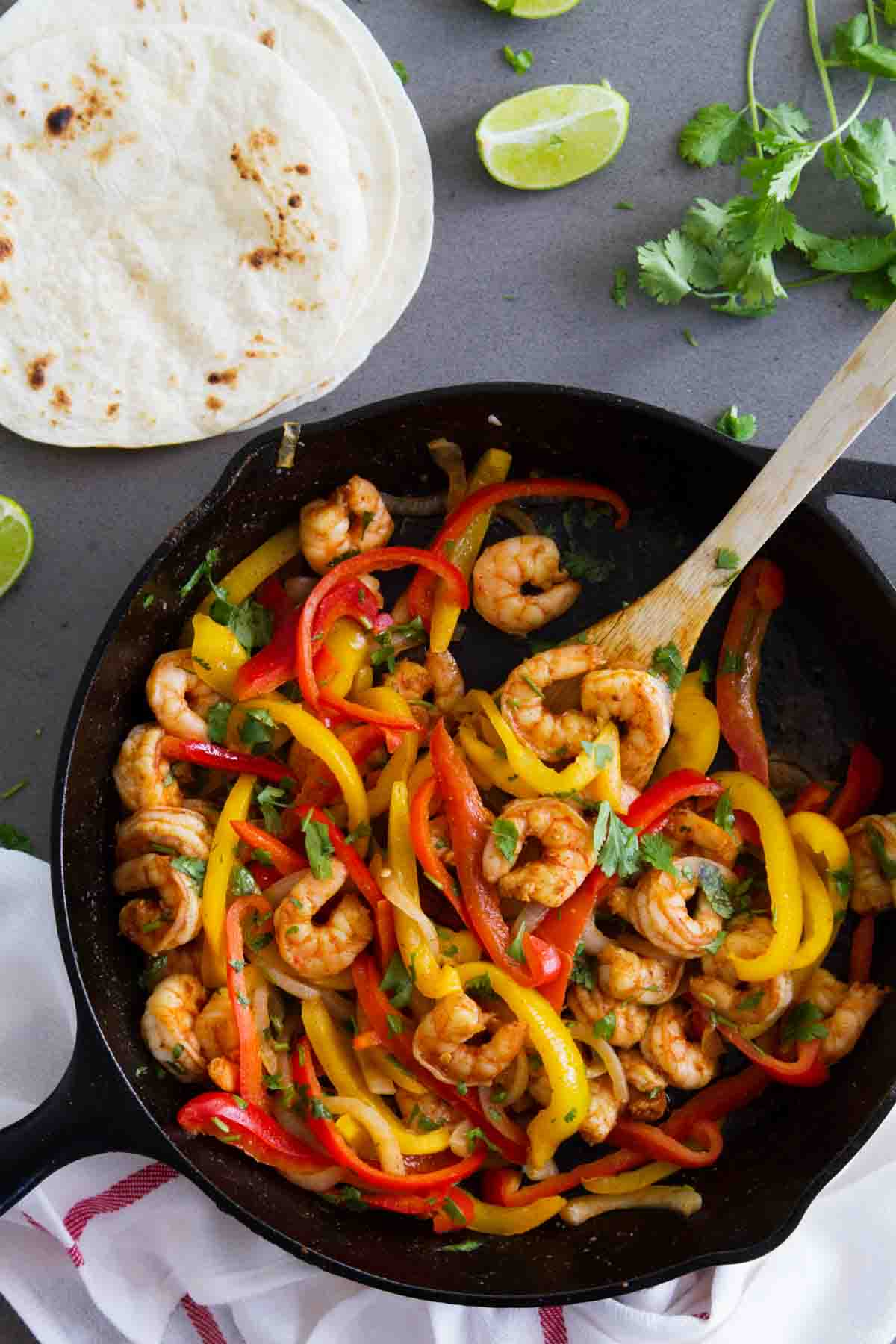 Shrimp Fajitas in a Cast Iron Skillet with tortillas on the side.