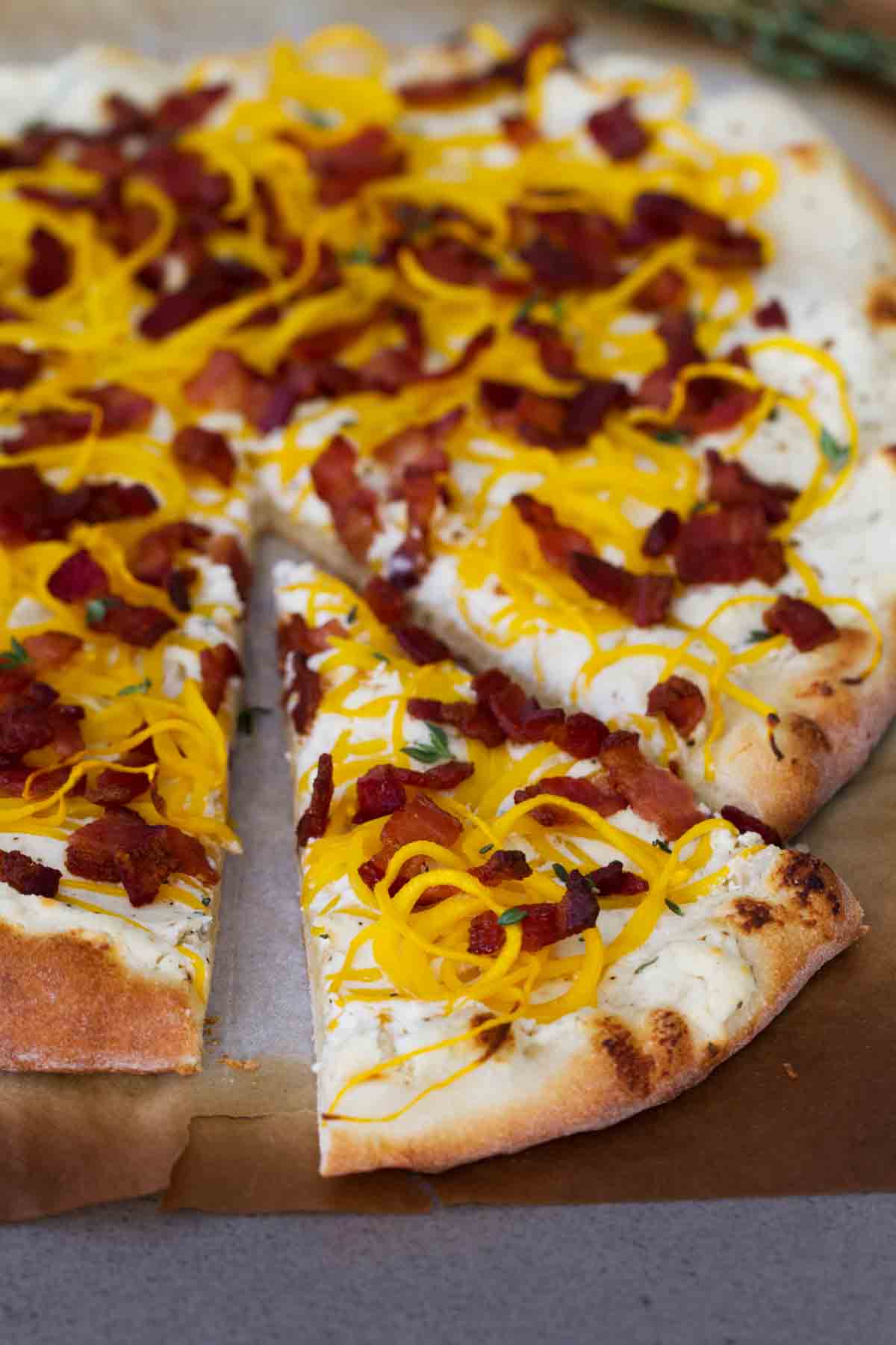 Bacon and Spiralized Butternut Squash Pizza with a slice being taken out.