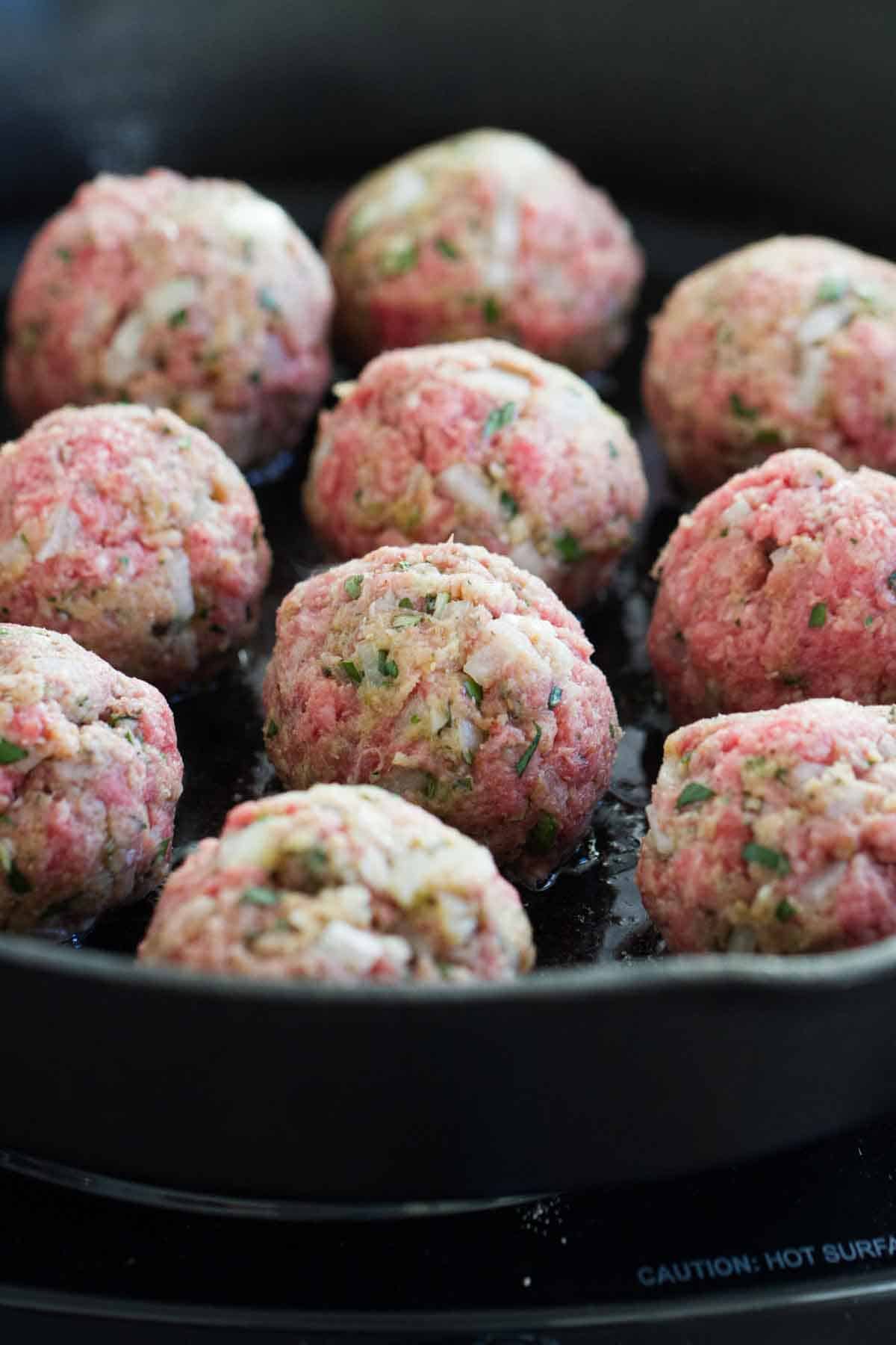 Meatballs cooking in a skillet. 