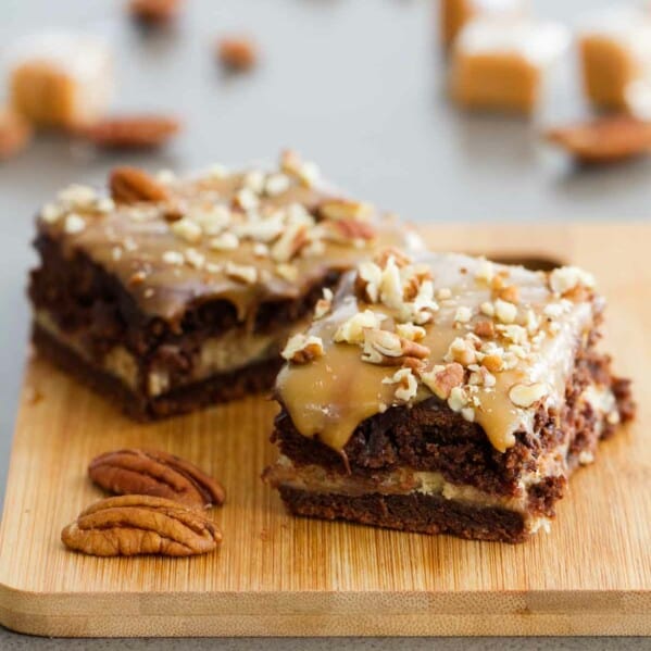 Turtle cheesecake cookie bars on a wooden cutting board.