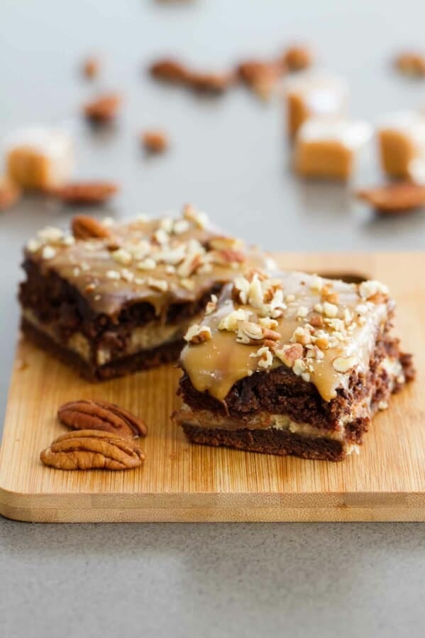 Turtle cheesecake cookie bars on a wooden cutting board.