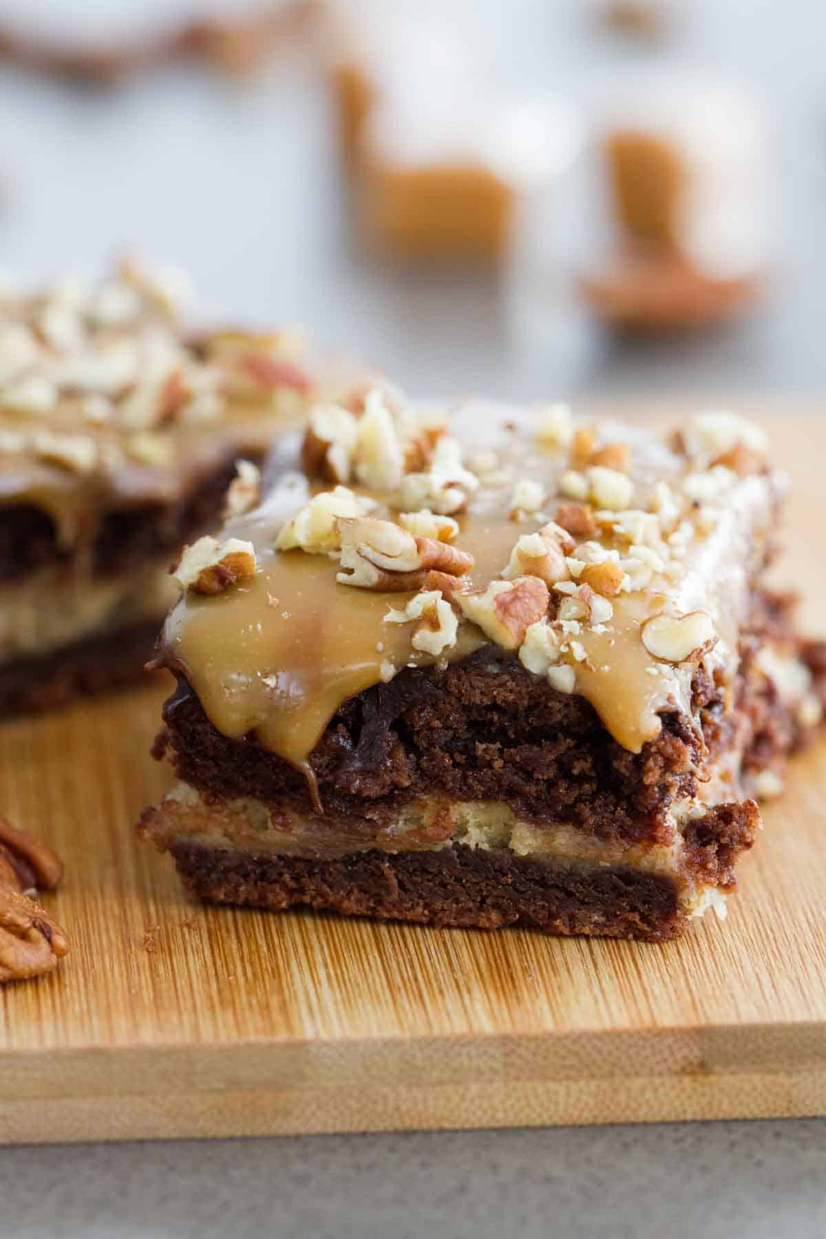 Turtle cheesecake cookie bar with dripping caramel on top.