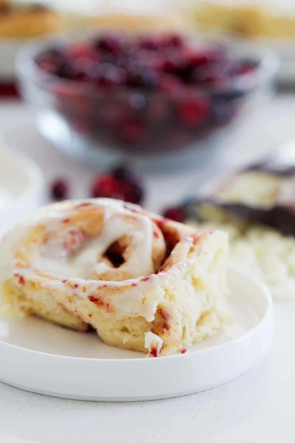 Light and fluffy and perfect for the holiday season, these Cranberry Cinnamon Rolls are filled with a cranberry filling and topped with a delicious and unique frosting. Cranberry Cinnamon Rolls on a small plate