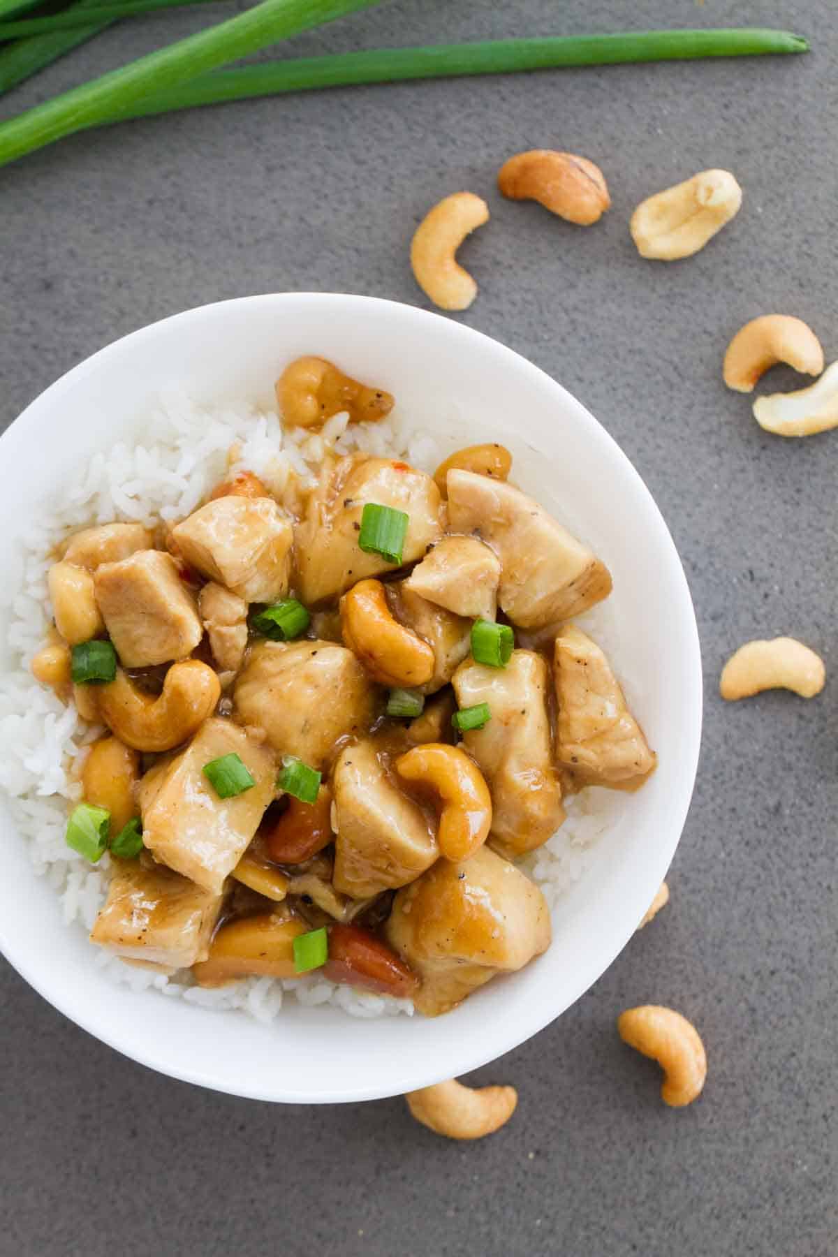 Bowl of Cashew Chicken over Rice with cashews on the table