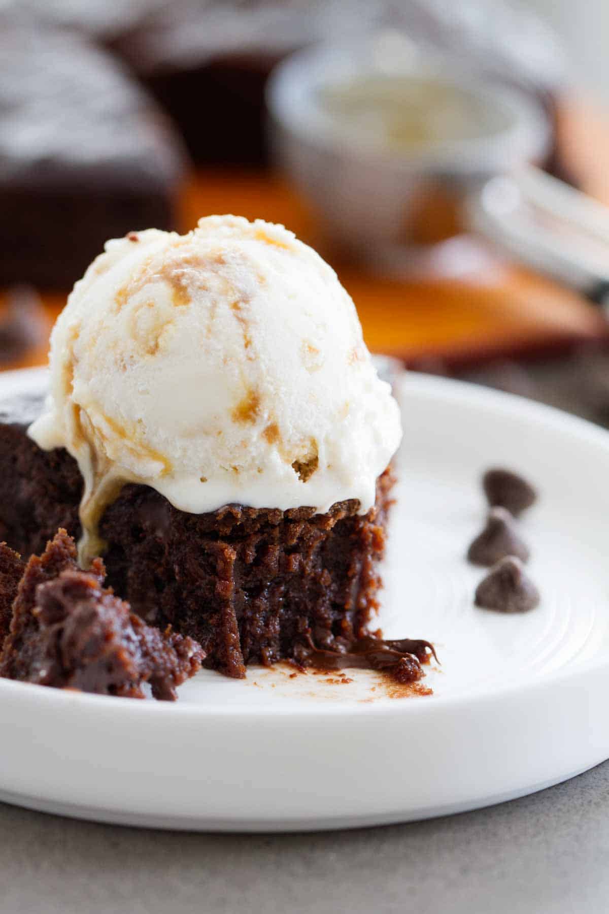 Brownie topped with ice cream with a bite taken from it.