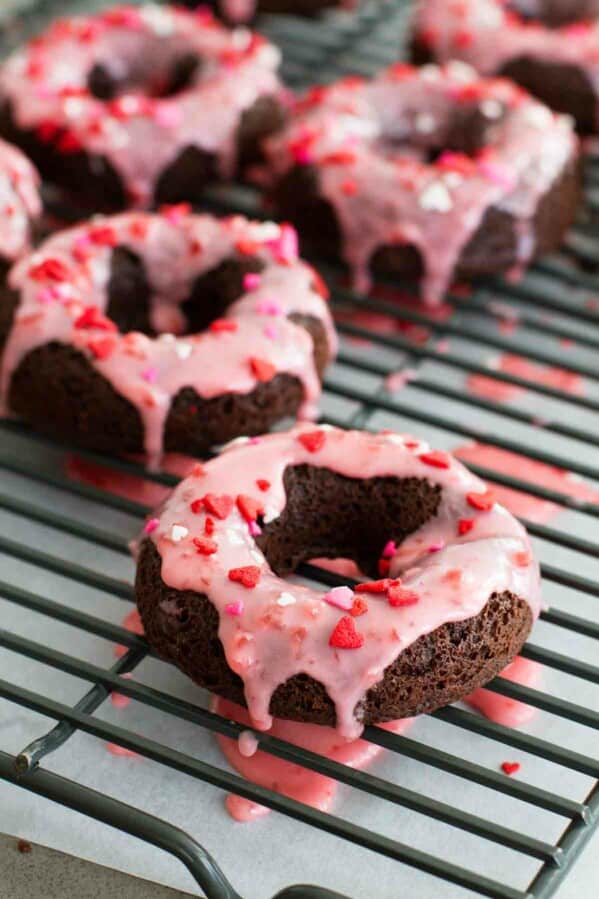 Baked Chocolate Donuts topped with cherry glaze and sprinkles.