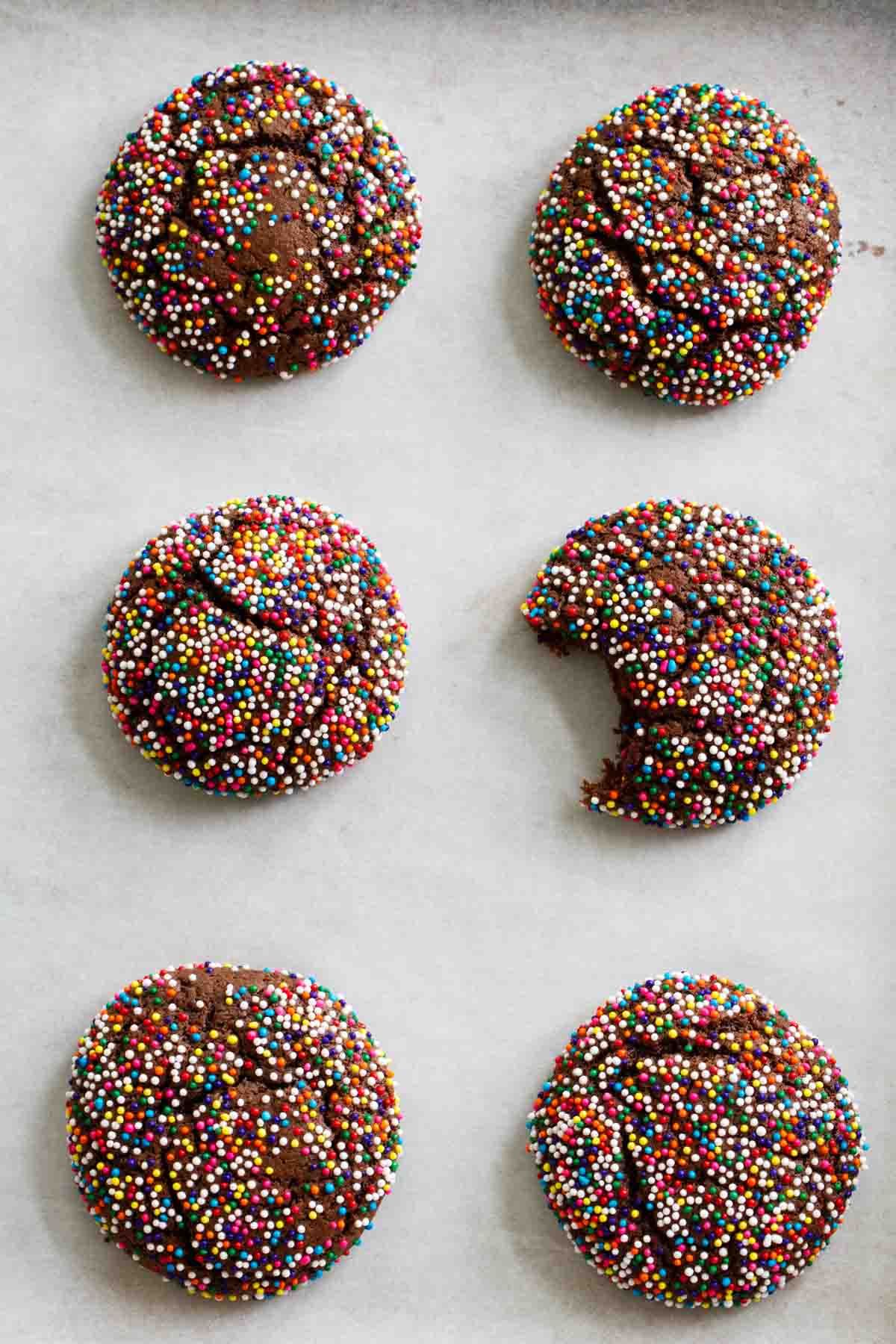 6 Chocolate Crinkle Sprinkle Cookies with a bite out of one