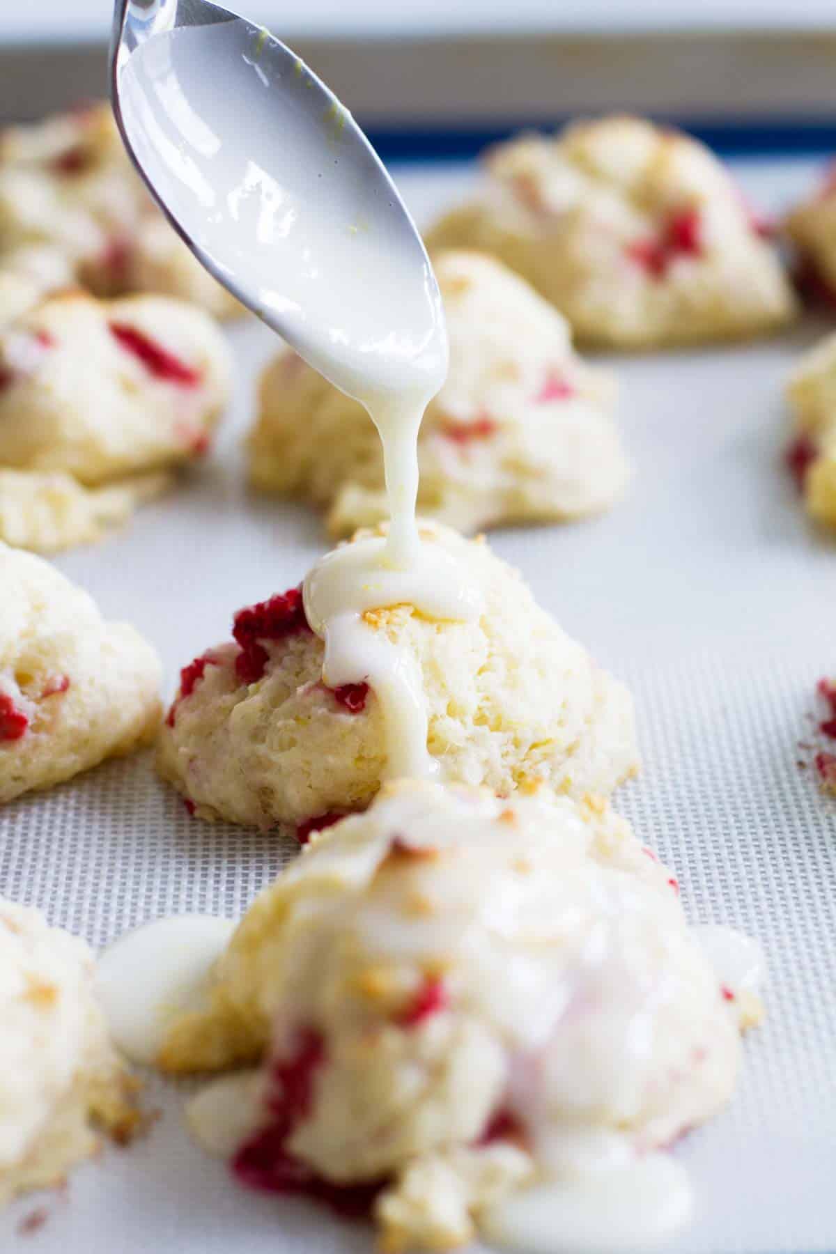 Pouring glaze onto Raspberry Lemon Breakfast Biscuits.