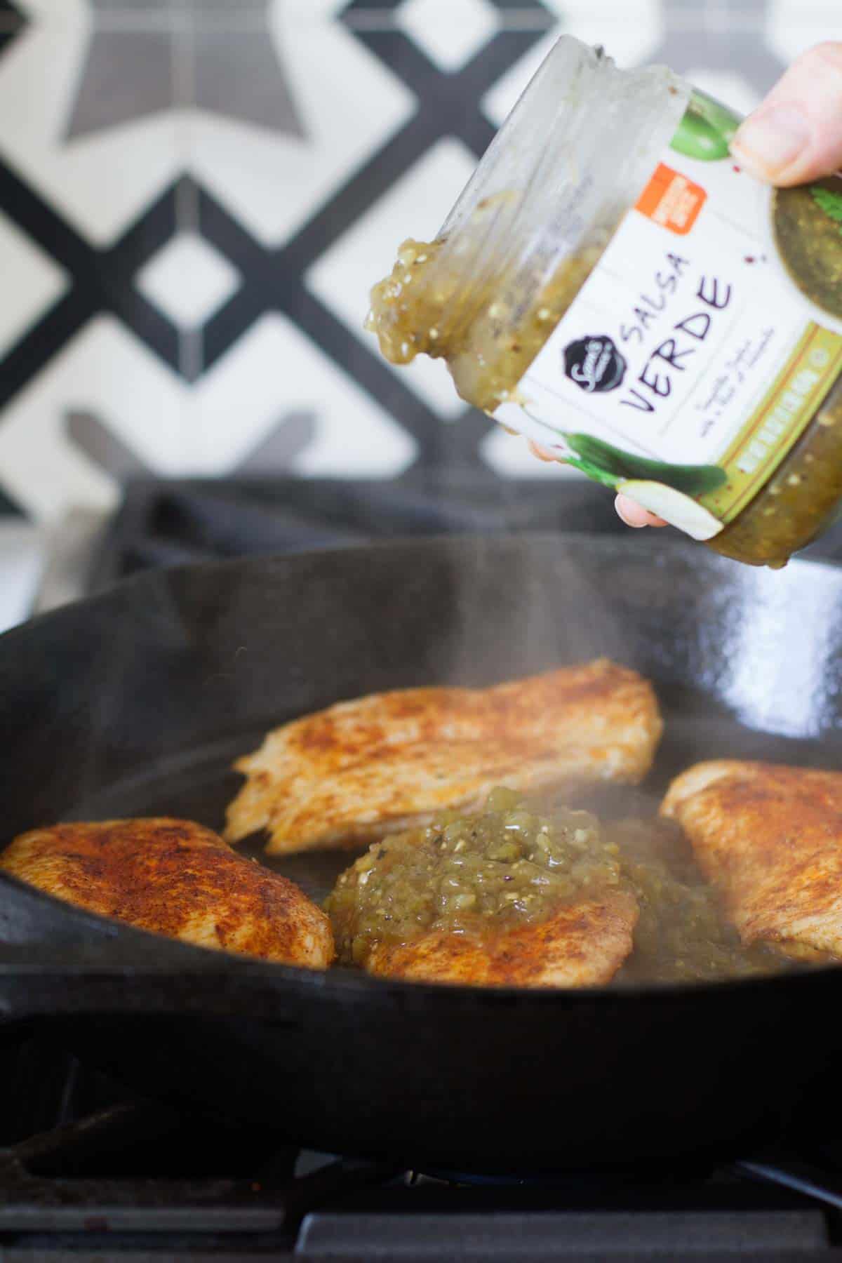 Pouring Salsa Verde over chicken to make salsa verde chicken.