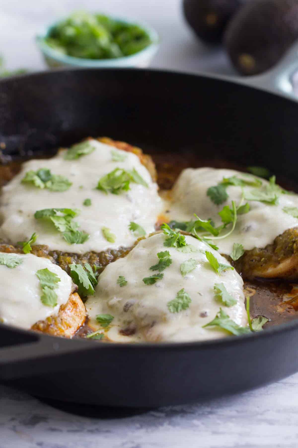 Skillet with Salsa Verde Chicken topped with cheese.