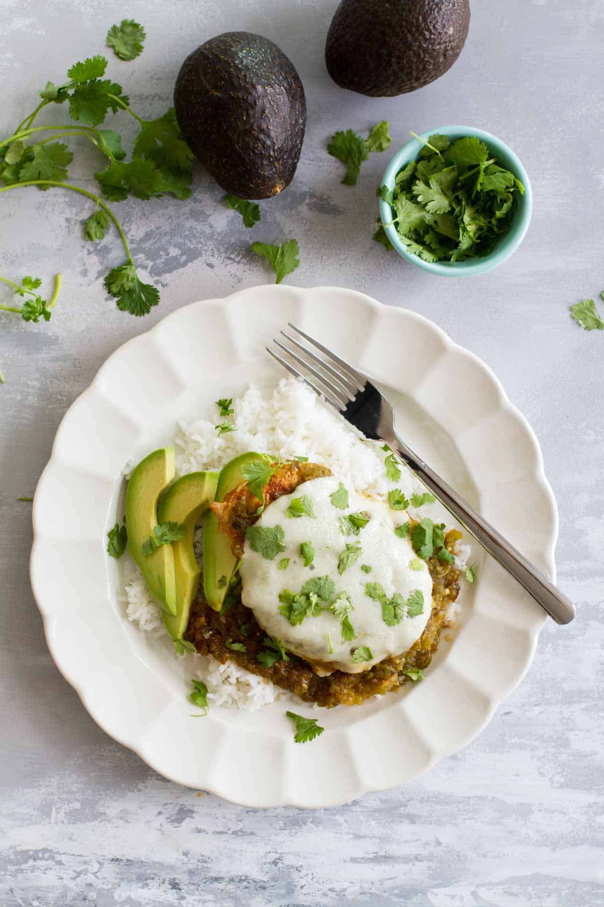 Salsa Verde Chicken over rice with sliced avocado on the side.