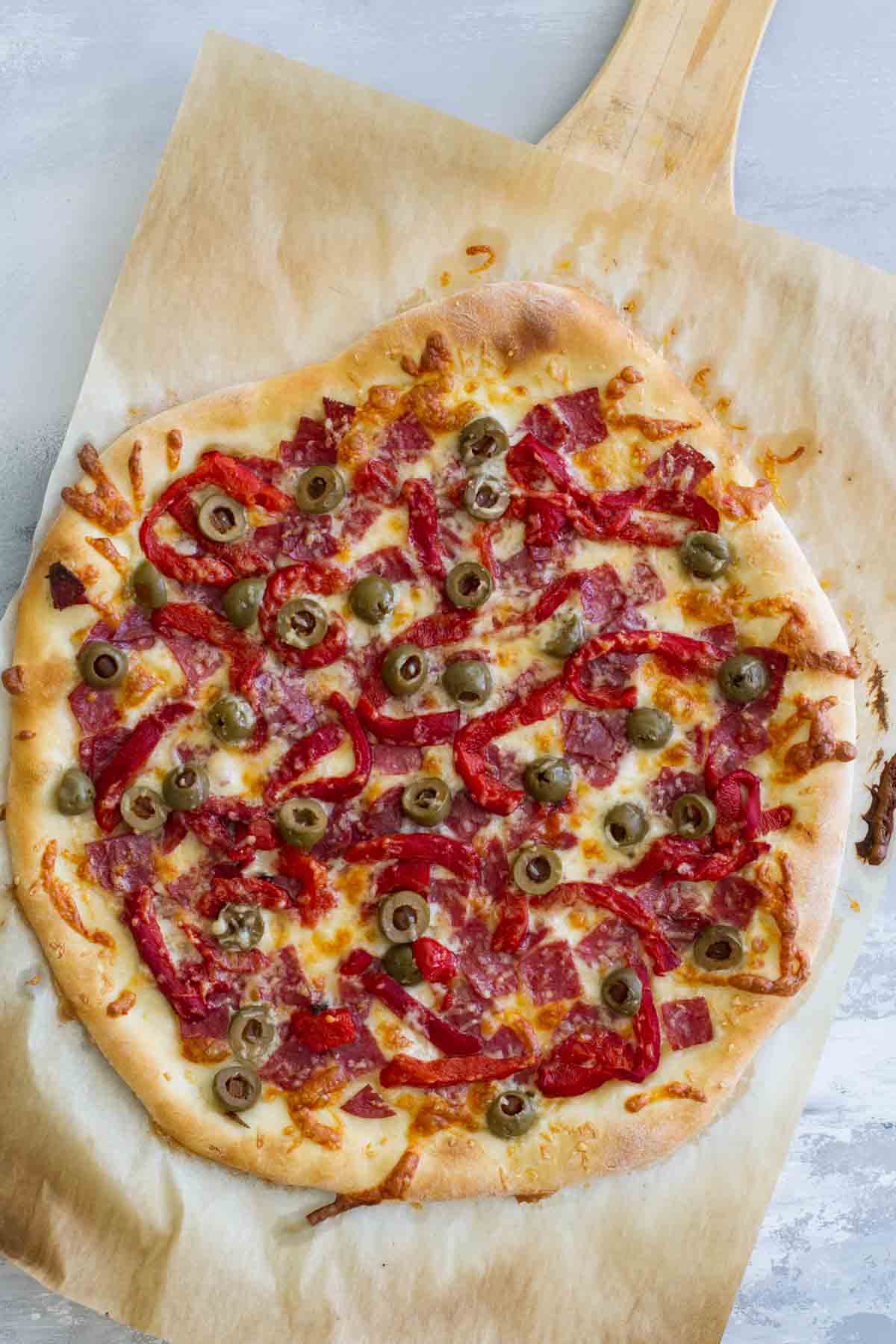 Whole Pizza Topped with Antipasto Ingredients on a pizza peel.