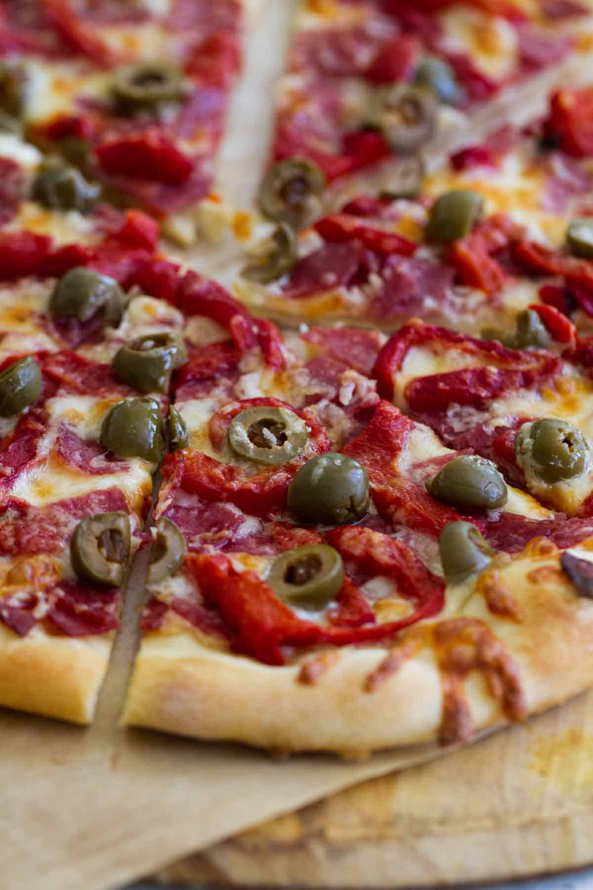 Piece of Antipasto Pizza topped with olives.