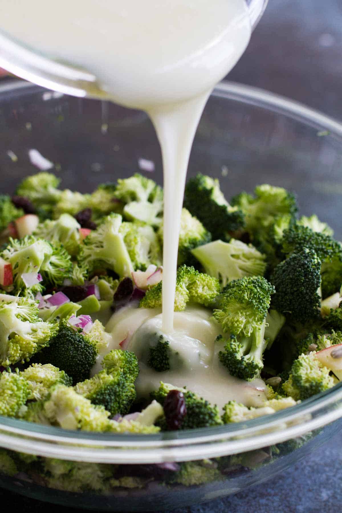 pouring dressing onto broccoli salad