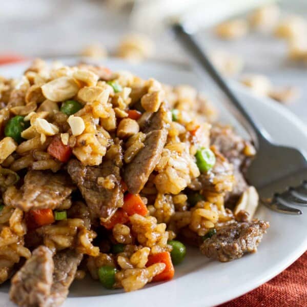 Beef stir fry with rice and vegetables on a plate with a fork.