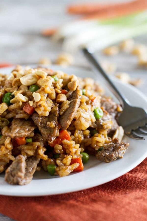 Beef stir fry with rice and vegetables on a plate with a fork.