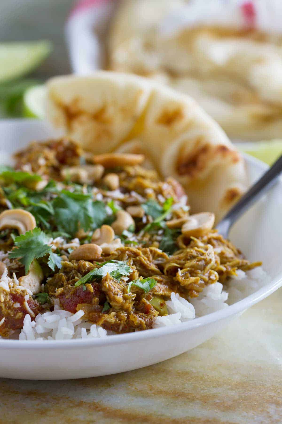 Bowl of coconut curry chicken with naan bread. 