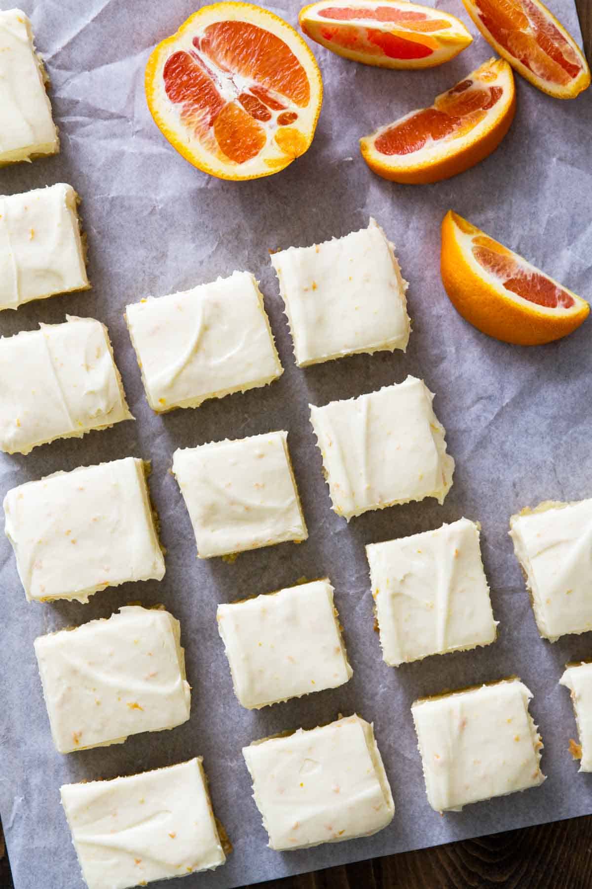 rows of orange blondies with fresh sliced oranges behind