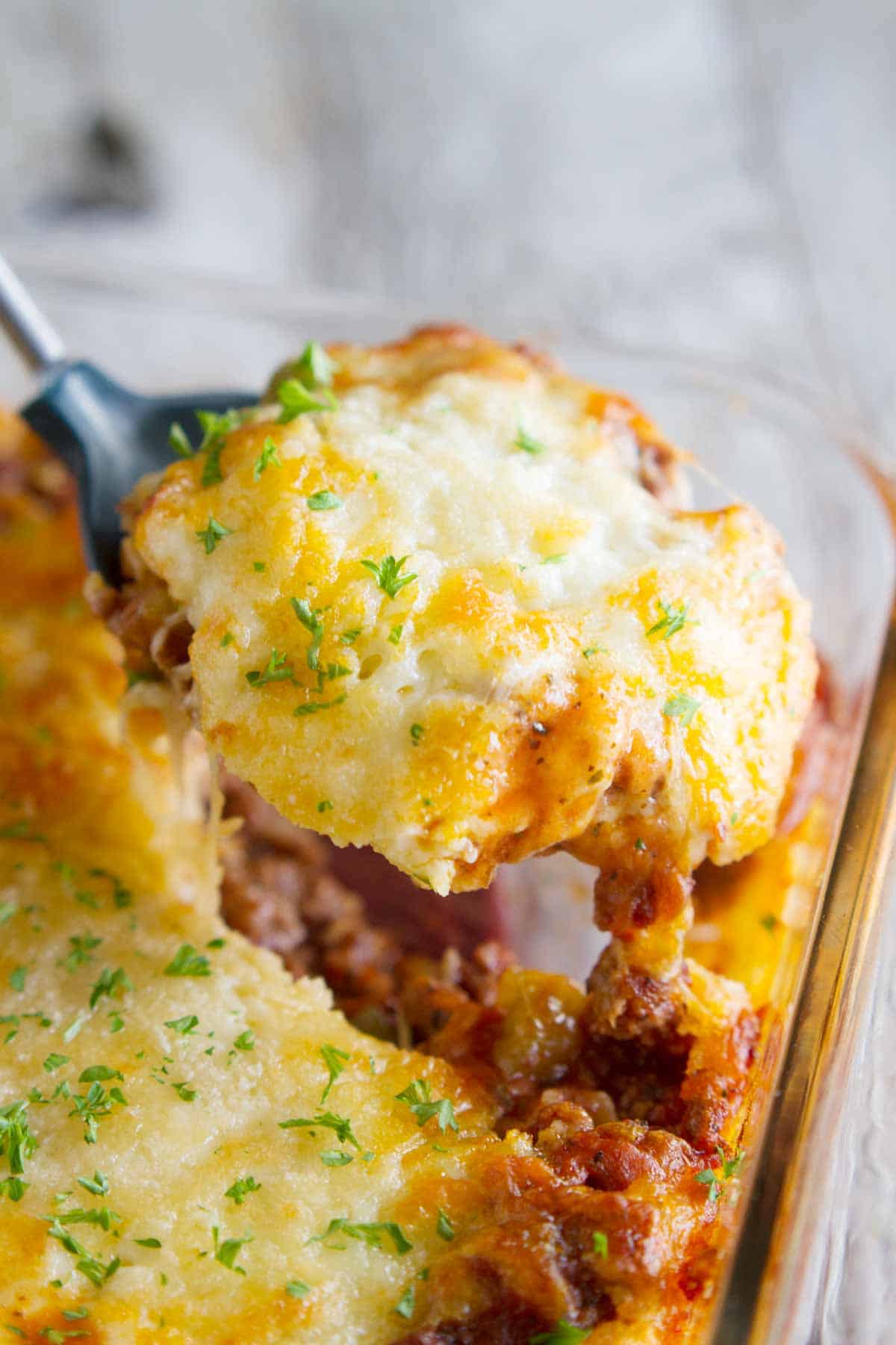 Puffed Up Pizza Casserole being scooped out of dish.