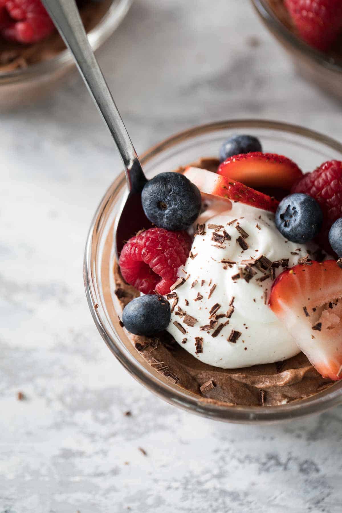 overhead view of chocolate mousse topped with whipped cream and berries