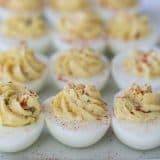 plate full of deviled eggs sprinkled with paprika