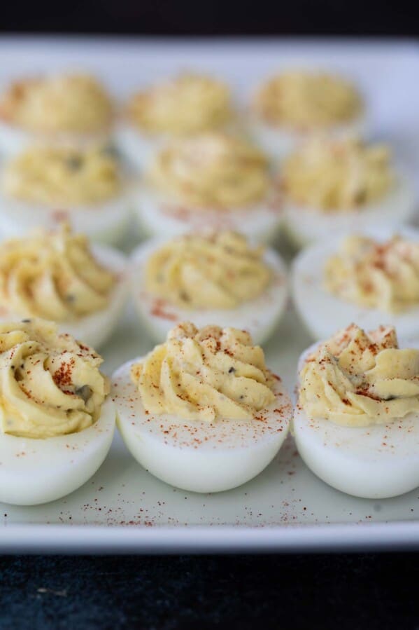 plate full of deviled eggs sprinkled with paprika