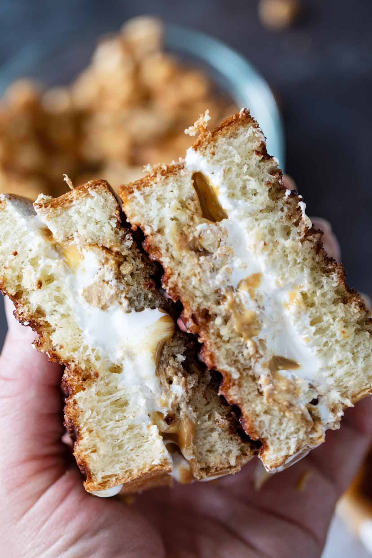 Hands holding a fluffernutter that is cut in half to show inside.