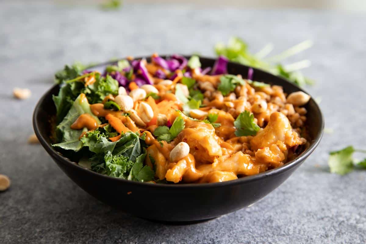 Buddha bowl topped with sauce and peanuts.