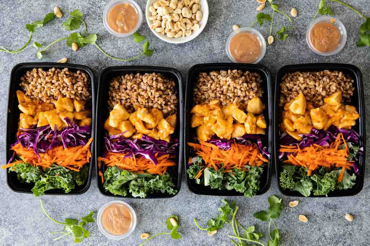 overhead view of 4 meal prep containers with buddha bowls with sauces on the side.