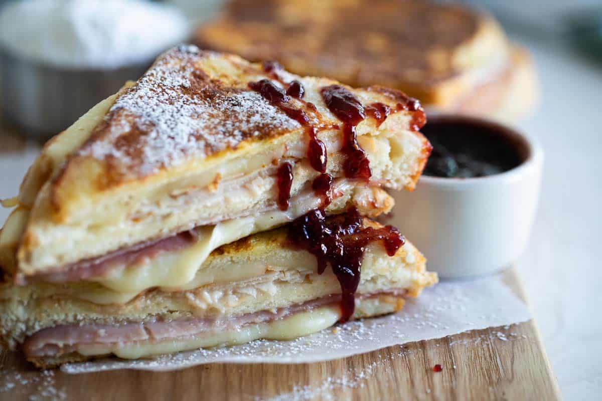 This is the ultimate make at home Monte Cristo Sandwich - with turkey, ham and cheese in a sandwich that is cooked French toast style. If desired, serve with powdered sugar and raspberry jam. It’s a sweet and savory combo that will convert even a skeptic! Monte Cristo Sandwich cut in half with jam drizzled on it
