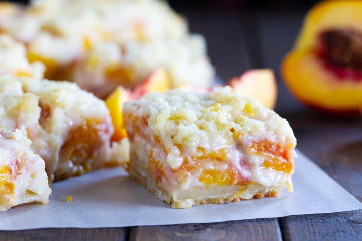 For a different take on a peach pie, try these Peaches and Cream Bars that have a shortbread crust, a creamy peach filling and a crumble topping. sliced peaches and cream bars on a piece of parchment
