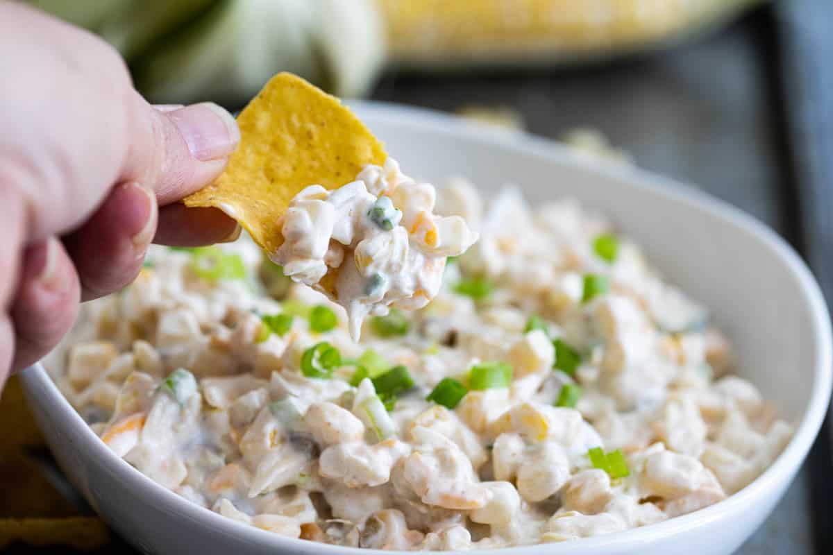 dipping a chip into corn dip with green chiles