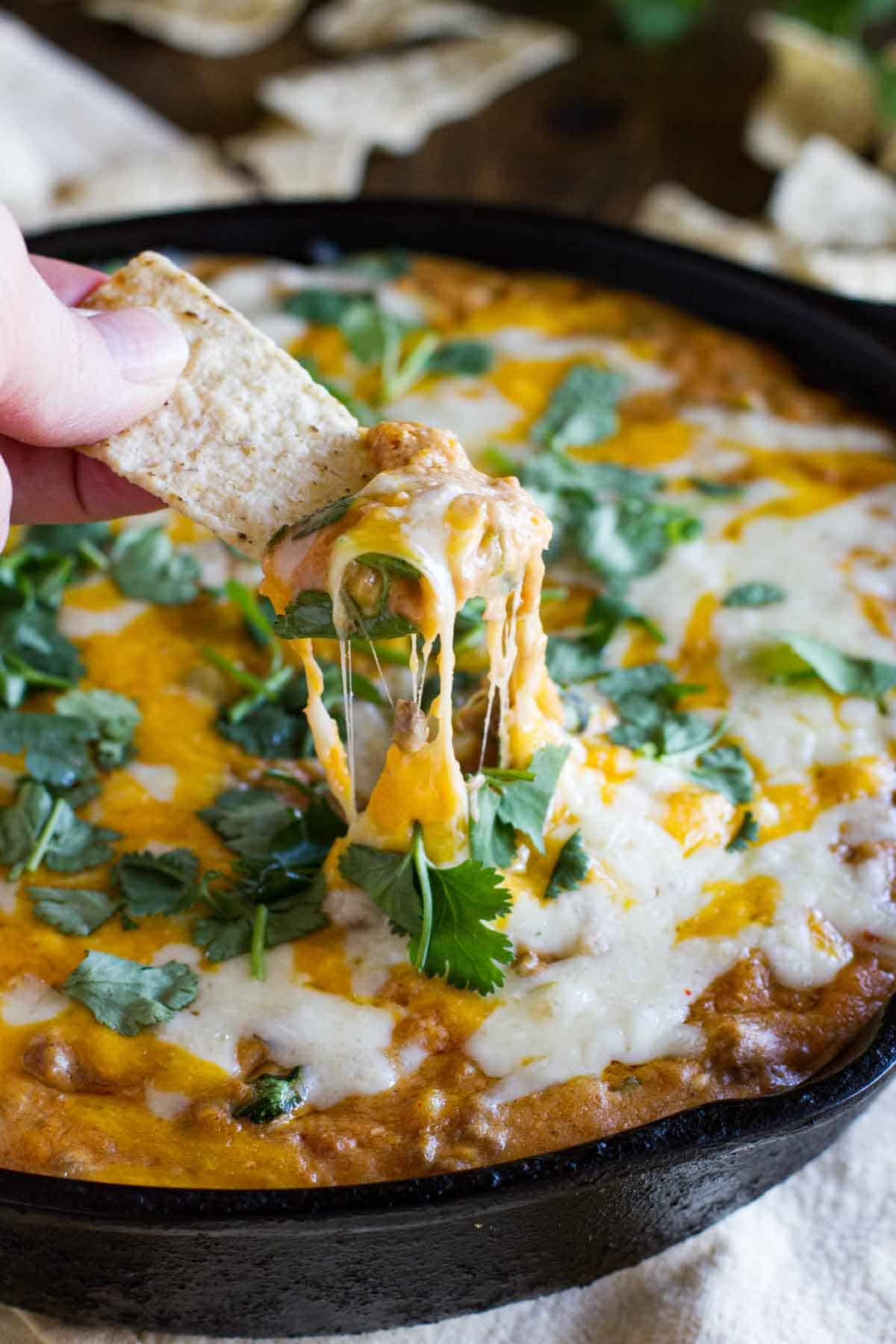 Eating cheesy hot beef and bean dip with a tortilla chip.