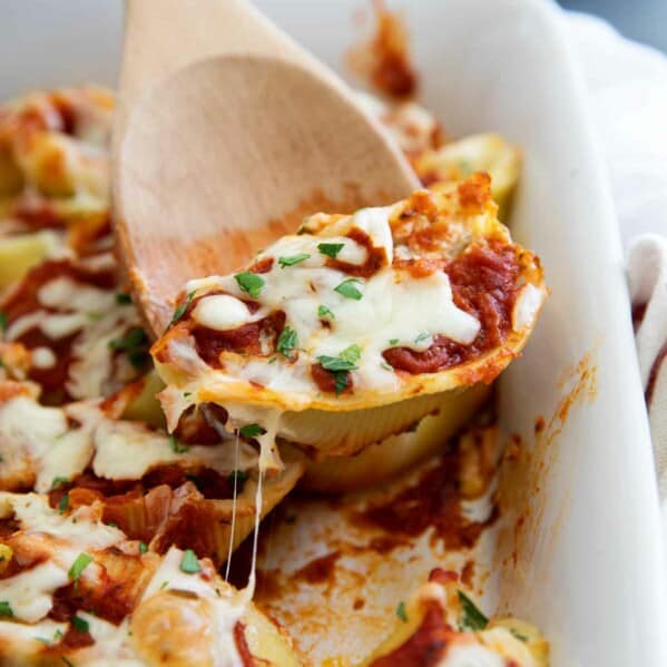Stuffed Shell in baking dish with wooden spoon scooping out